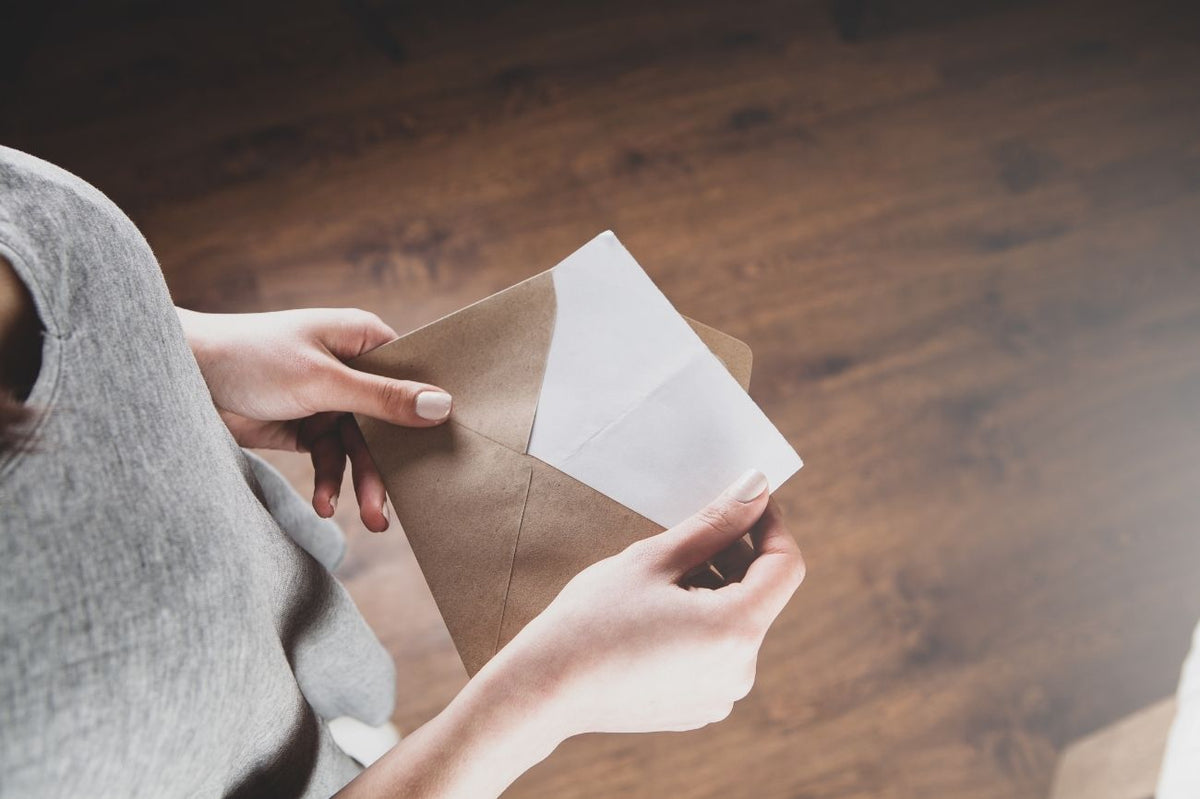 Hands holding an open envelope with a letter inside